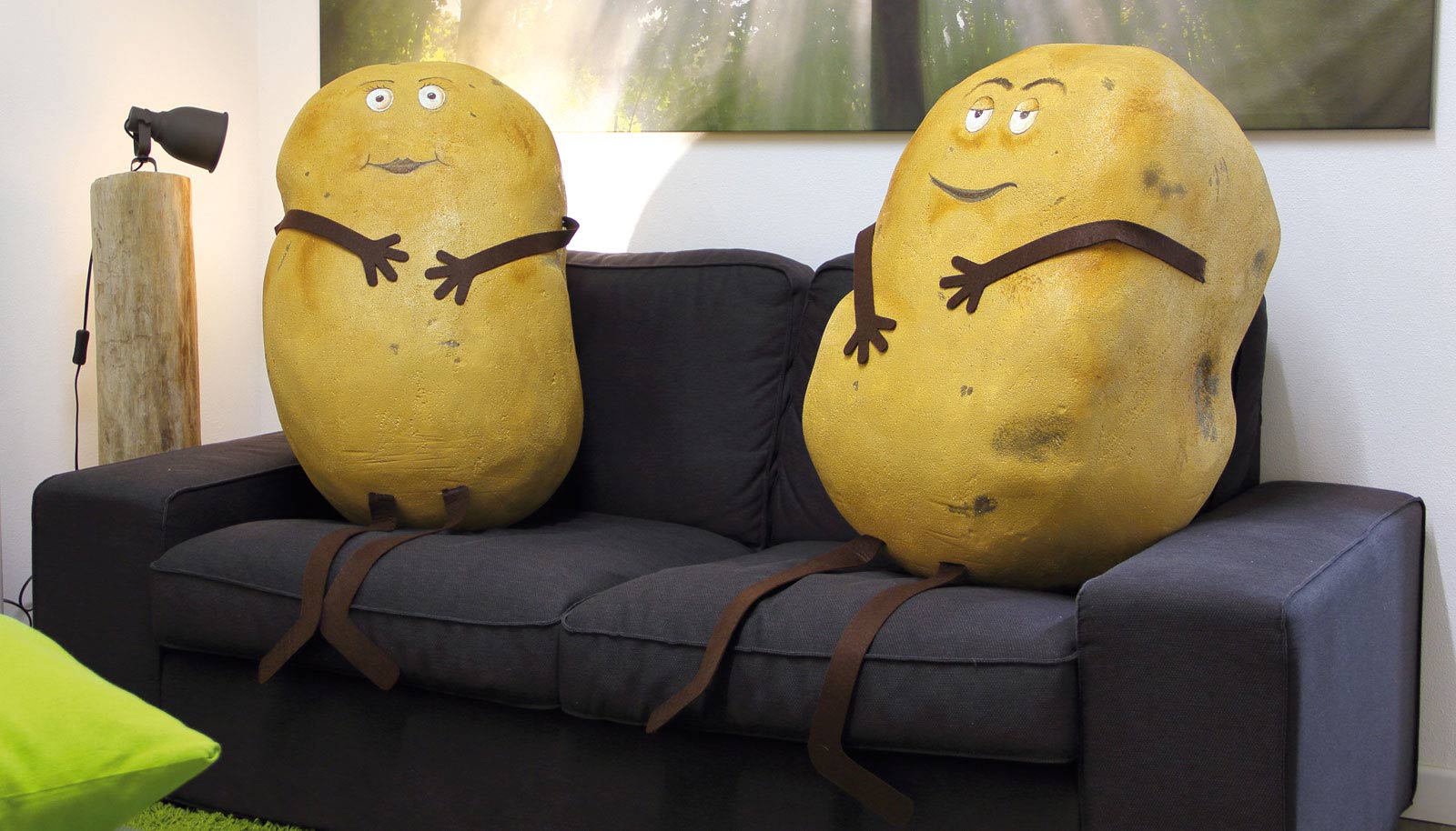 scultura figurativa di due patata di dimensione umana sedute su un divano